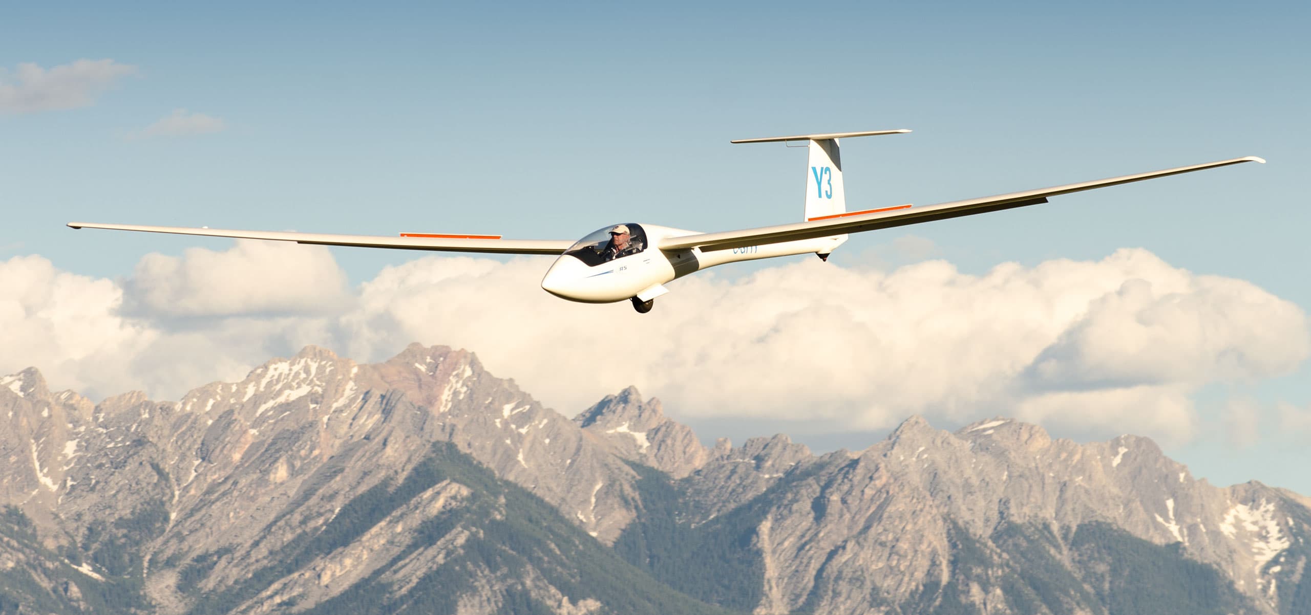 Glider banking above snow-capped Rocky Mountain peaks