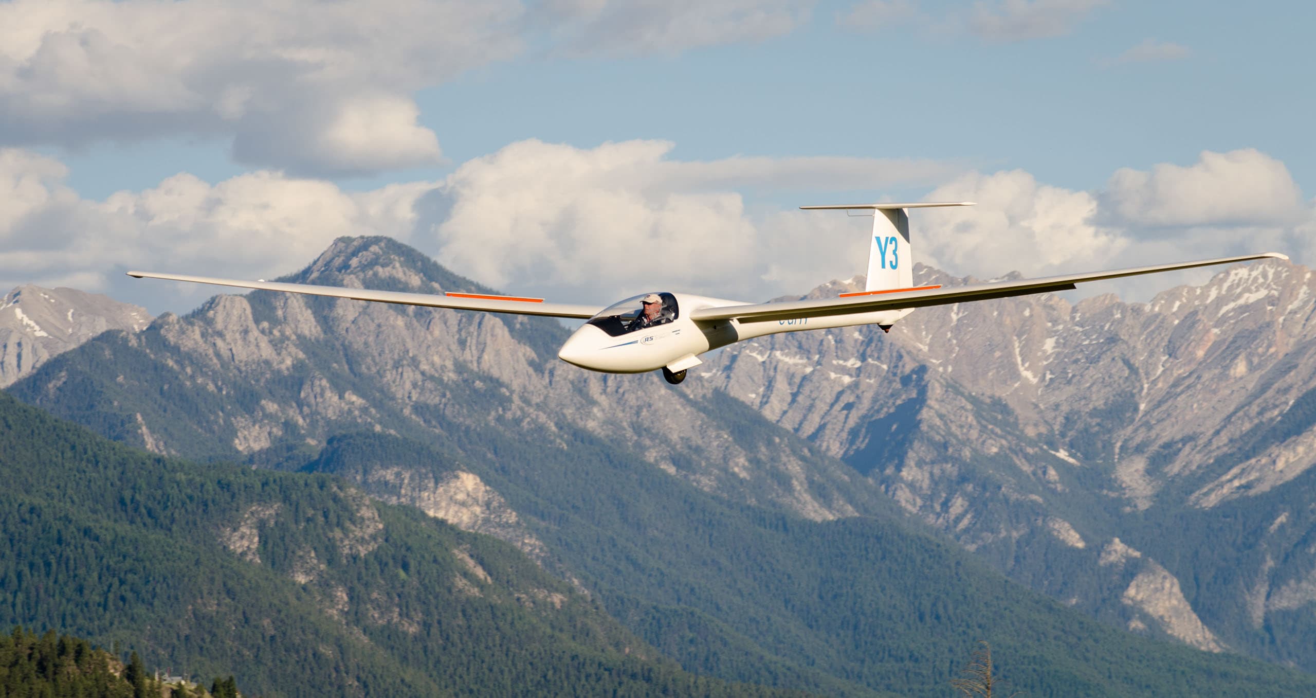 Glider gliding over forested mountain ridges
