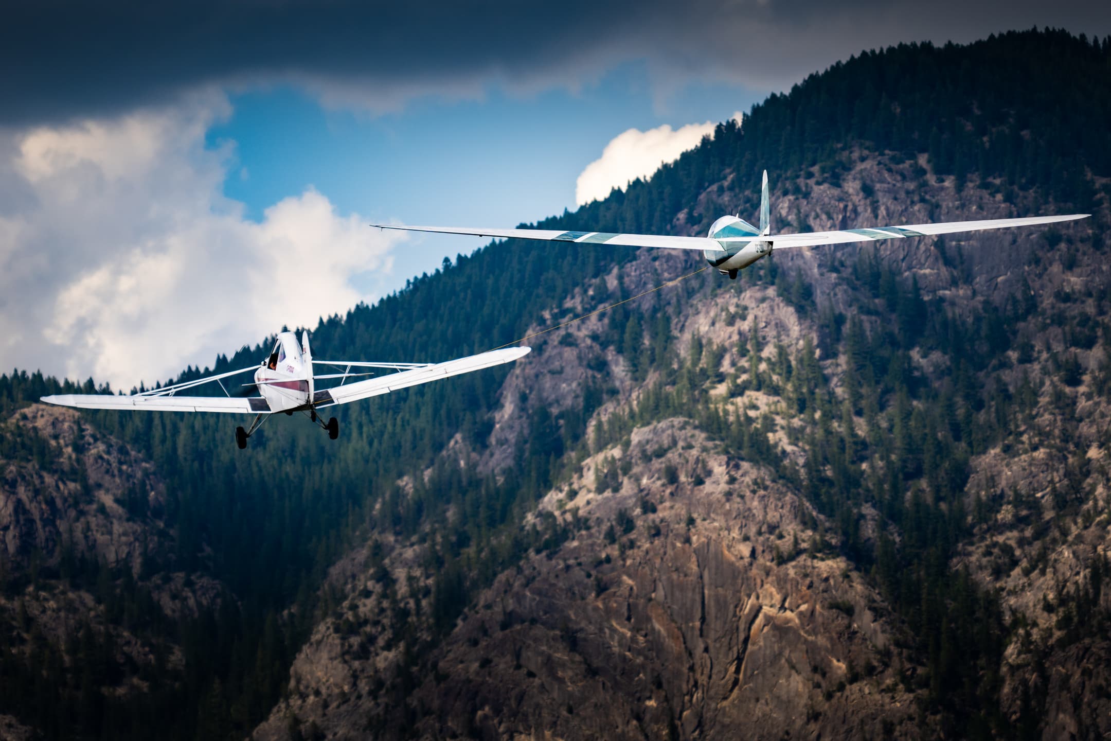 Glider on aerotow behind the towplane over the Rocky Mountains