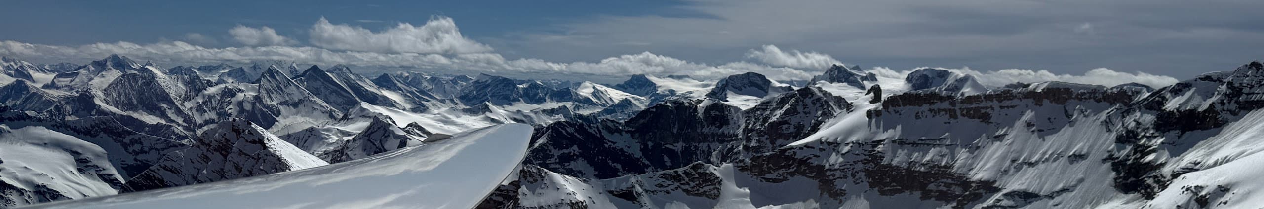 Cockpit view over the glider's wing, soaring above the snow-capped Rocky Mountains near Invermere