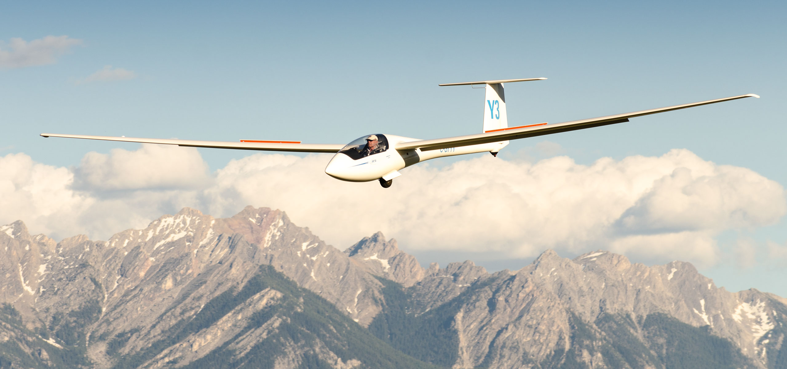 Glider banking above snow-capped Rocky Mountain peaks
